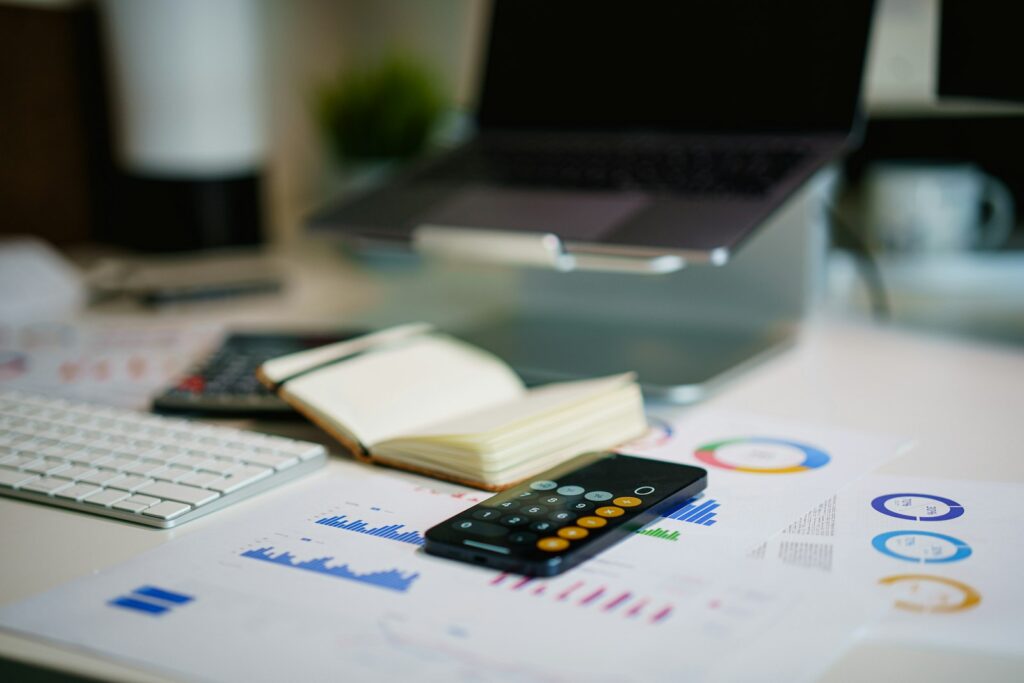 Office desk with a smartphone and financial charts, representing a firm's compliance paperwork