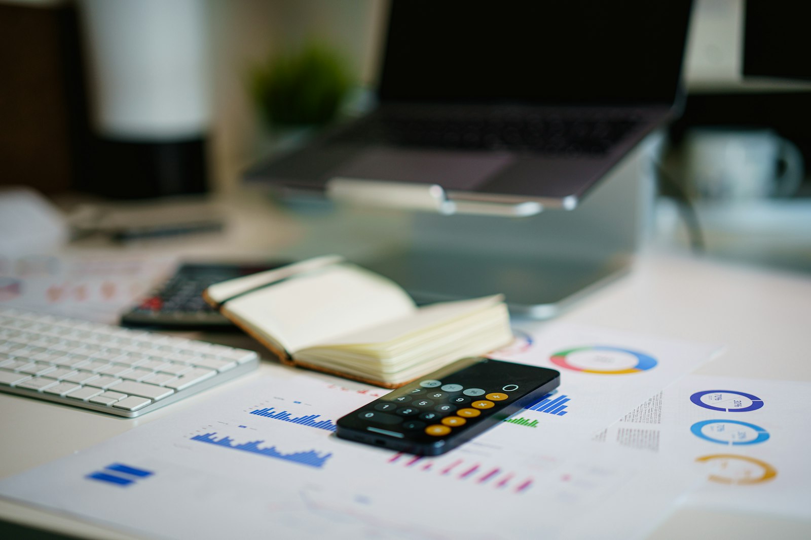Office desk with a smartphone and financial charts, representing a firm's compliance paperwork