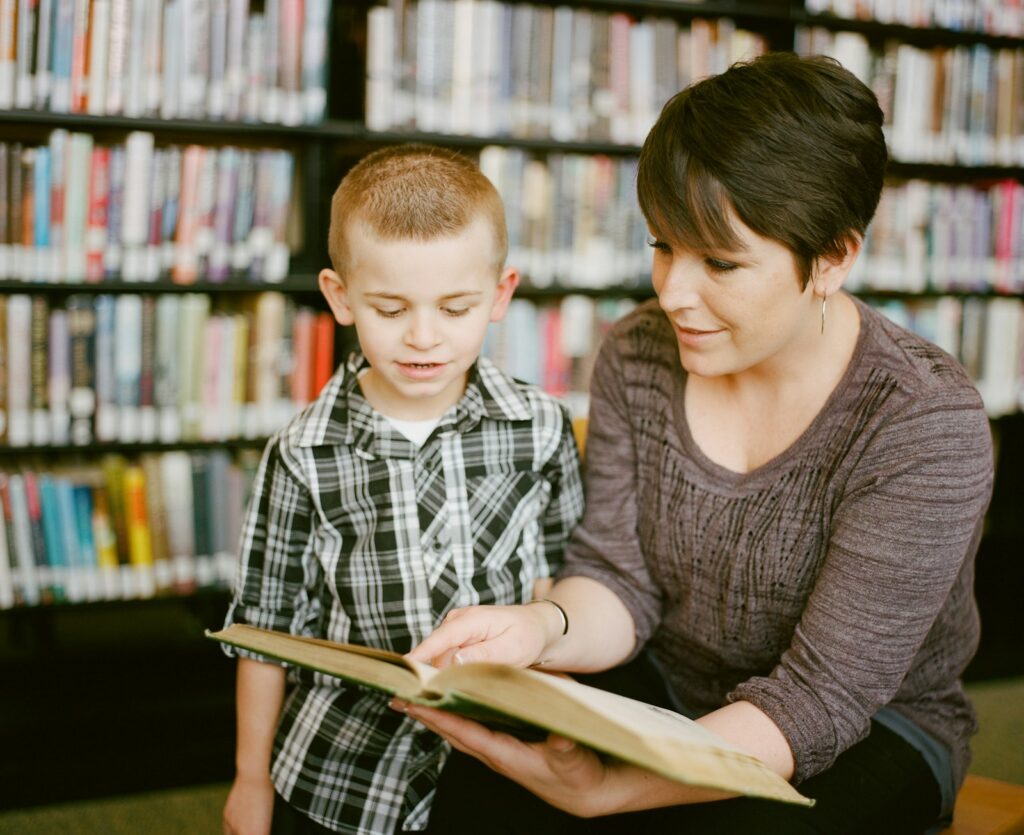 Woman and young child reading a book together in a library