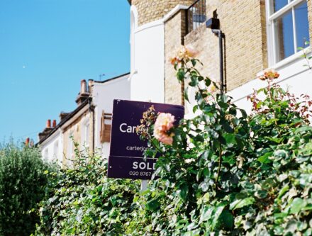 Sold sign and roses in front of a house after a property sale