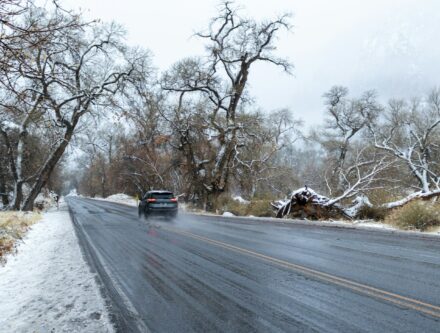 Car driving along a wet road with patches of snow piled either side in winter