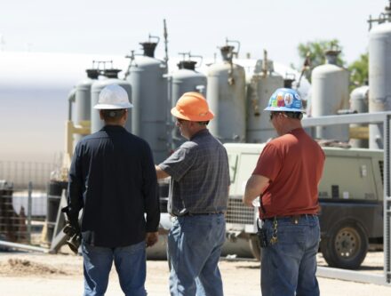 Men in hard hats discussing equipment, highlighting the importance of workplace safety