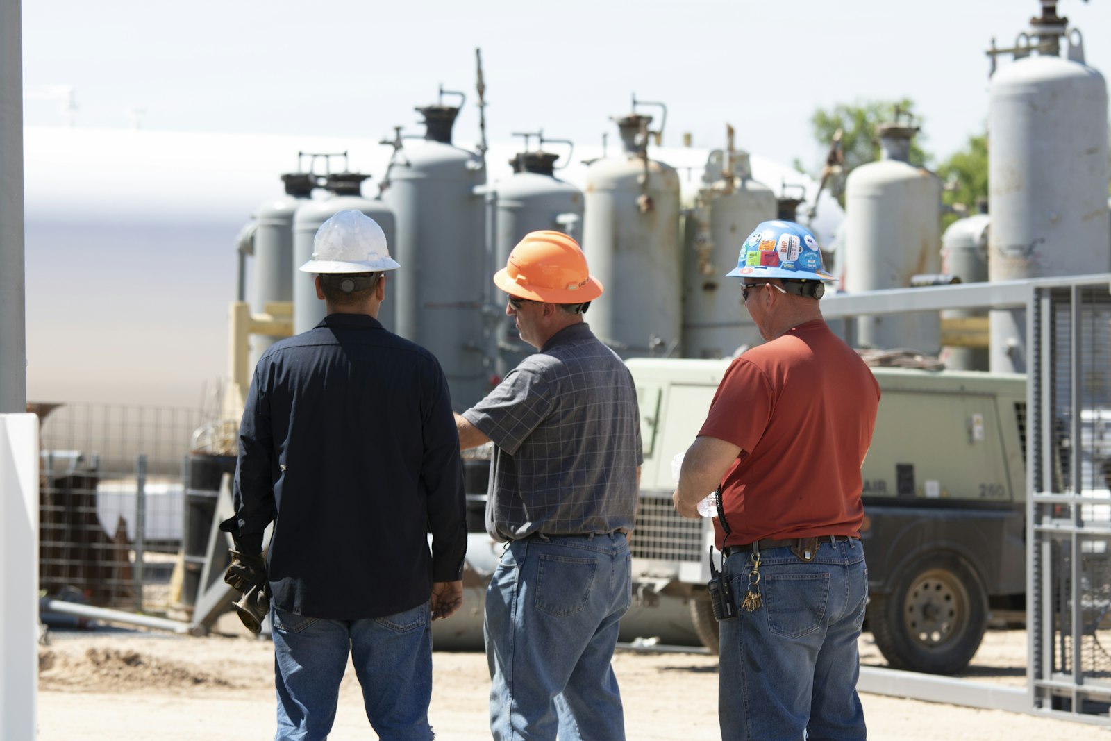Men in hard hats discussing equipment, highlighting the importance of workplace safety