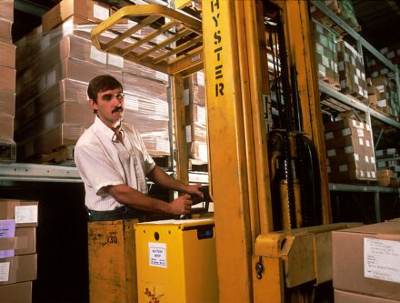 Man driving a yellow forklift inside a warehouse