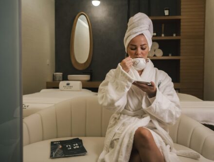 Woman in a white robe sitting on a white couch, relaxing during a spa break