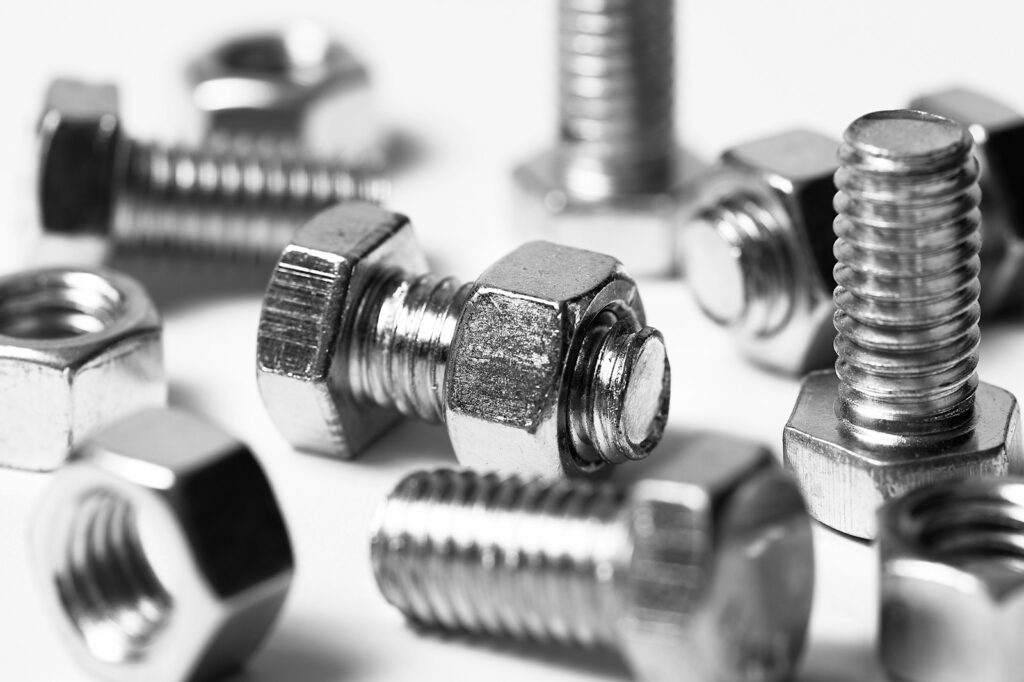 Close-up of scattered silver nuts and bolts on a white background