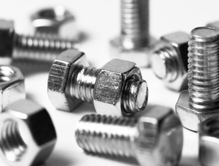 Close-up of scattered silver nuts and bolts on a white background