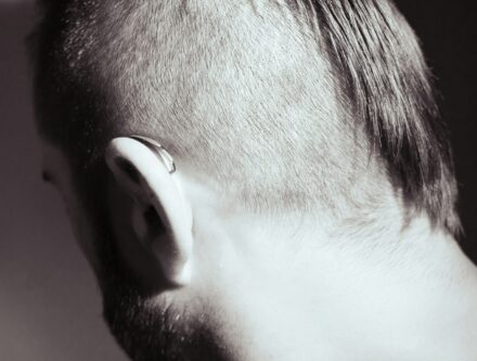 Close-up black and white shot of a person's ear with hearing aids