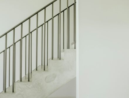 Staircase with a grey steel handrail running alongside the steps