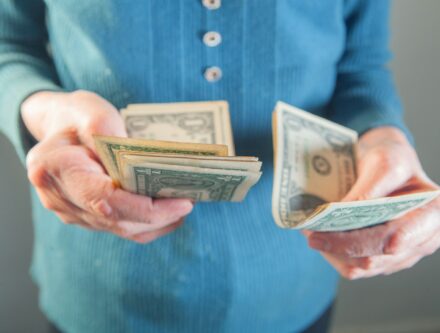 Close-up of an elderly woman holding money in her hands, highlighting financial vulnerability