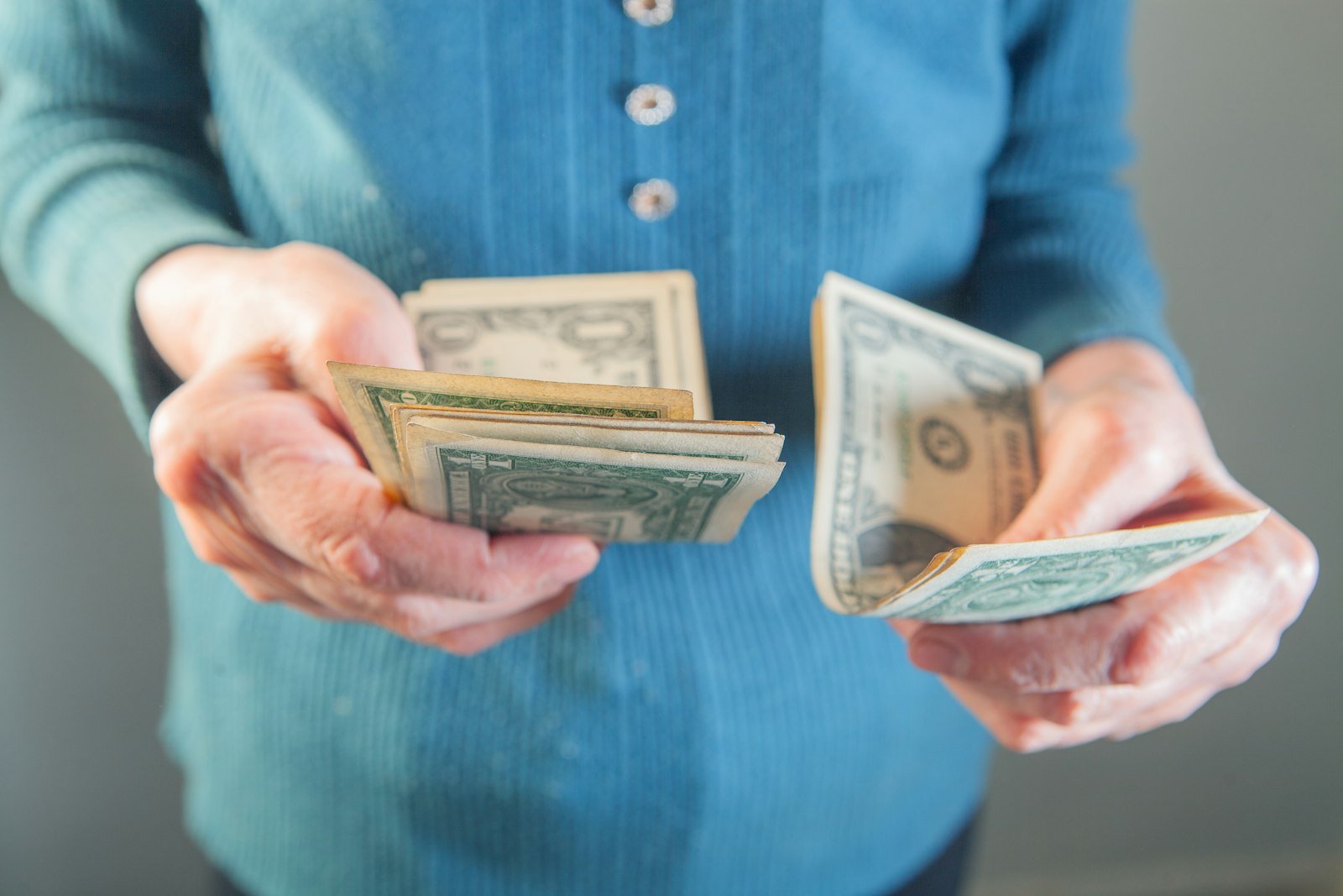 Close-up of an elderly woman holding money in her hands, highlighting financial vulnerability