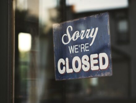 Sorry we're closed sign hanging on a glass shop door