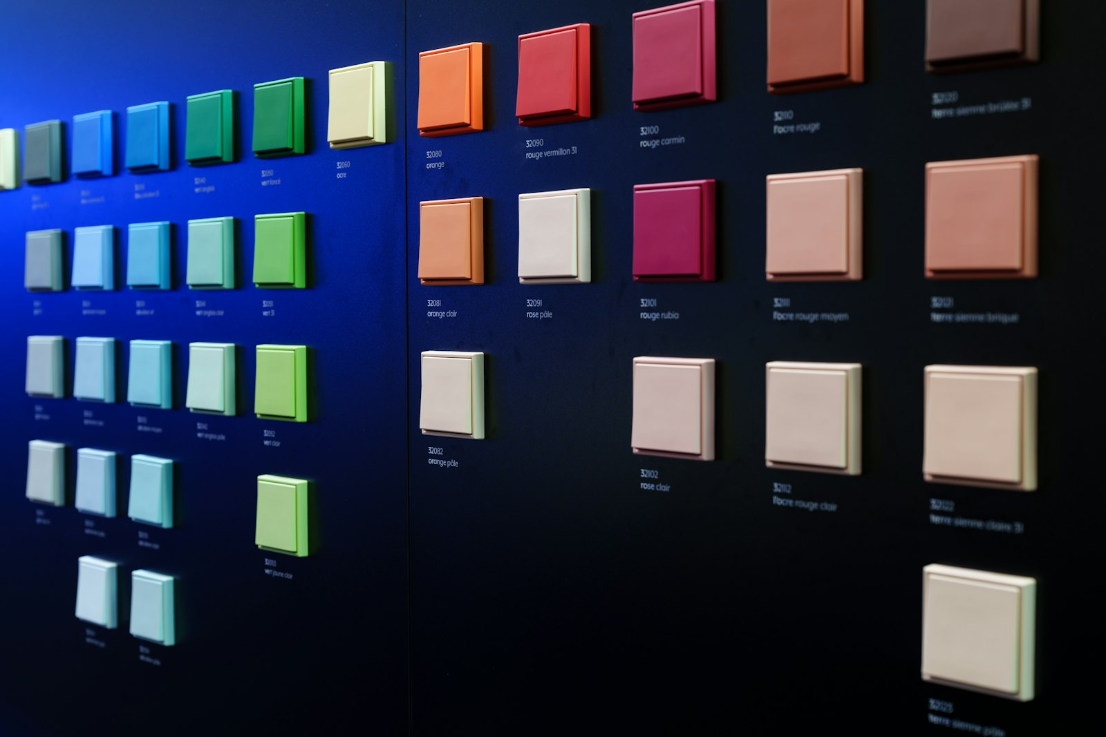 Wall covered in square paint samples of many colours, for comparing undertones