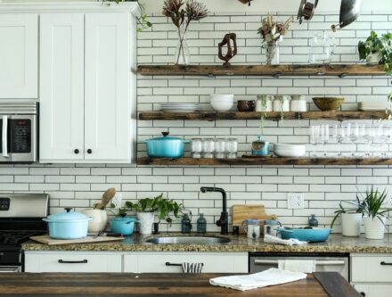 Kitchen with white cabinets and open wooden shelves holding cookware for tidy storage