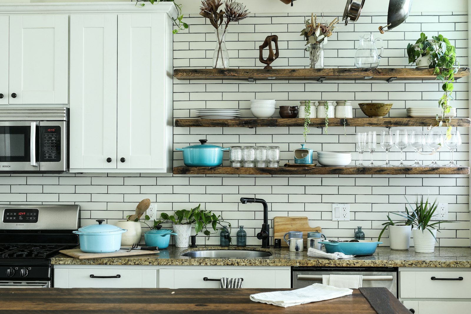 Kitchen with white cabinets and open wooden shelves holding cookware for tidy storage