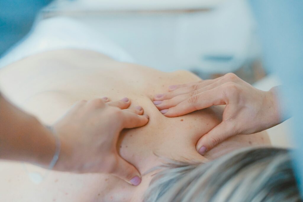 Person massaging the back of a woman during a massage treatment