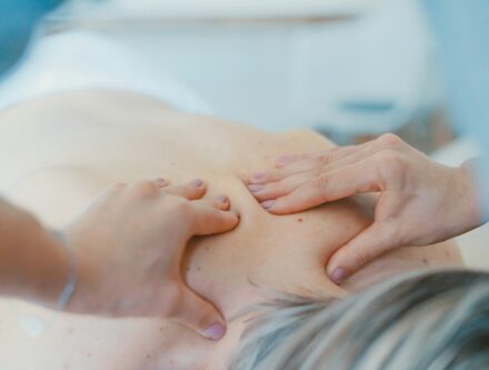 Person massaging the back of a woman during a massage treatment