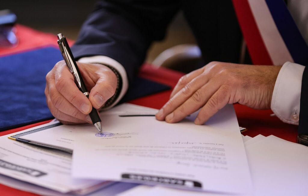 Person signing a document with a pen