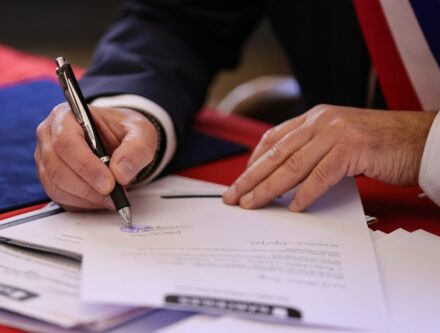 Person signing a document with a pen