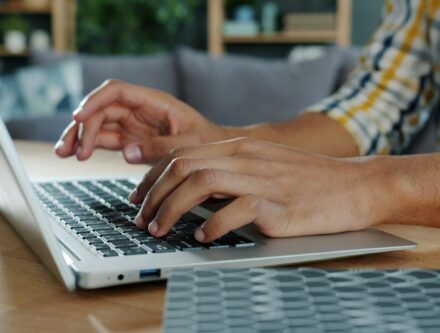 Person typing on a laptop at a desk, where one careless click can cause harm