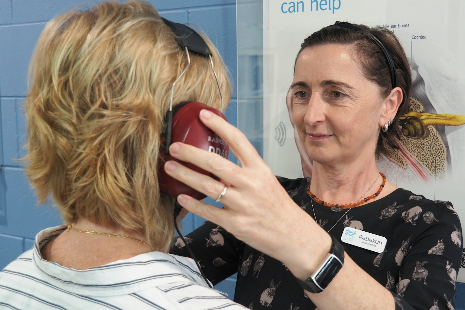 Audiologist placing headphones on a woman ready for her hearing test